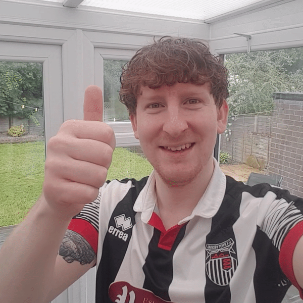 A person wearing a Grimsby Town FC shirt putting his thumb up