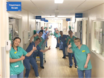 A group of medical staff in scrubs with their thumbs up
